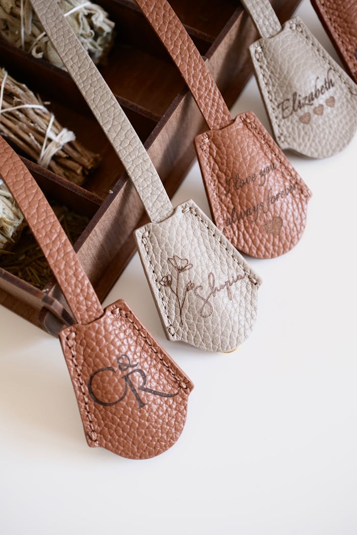Stylish leather bag tags with monograms in an elegant wooden box, perfect for personalized travel accessories.